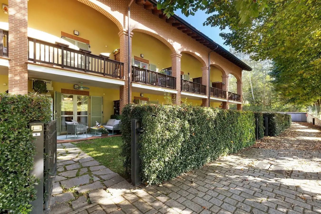 Il Granaio visto dal giardino, con i balconi in legno e le siepi